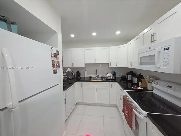 a kitchen with granite countertop a sink and white cabinets
