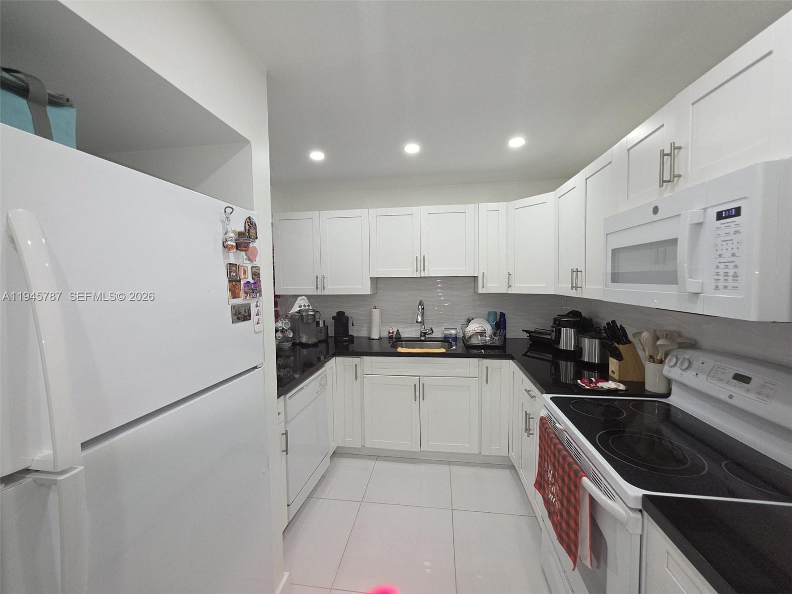 6970 Northwest 186th Street, Unit 3307 Hialeah, FL 33015 - Photo 8 of 21 a kitchen with granite countertop a sink and white cabinets