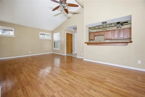 a view of an empty room with a window and wooden floor