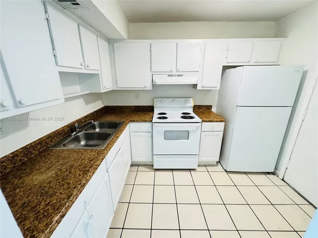 a kitchen with a stove a refrigerator and white cabinets