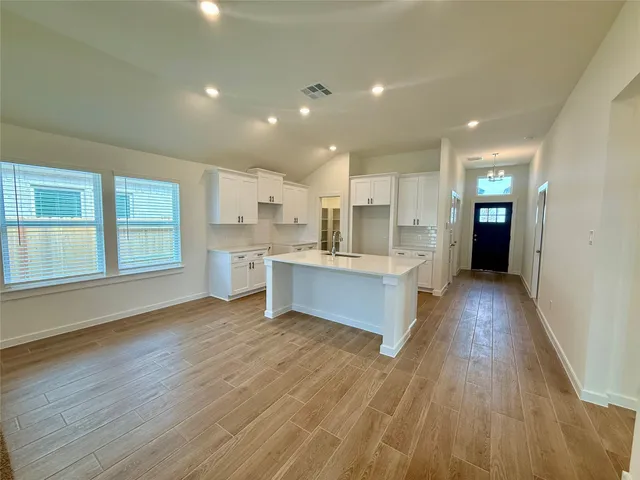 a large kitchen with kitchen island a sink wooden floor and stainless steel appliances