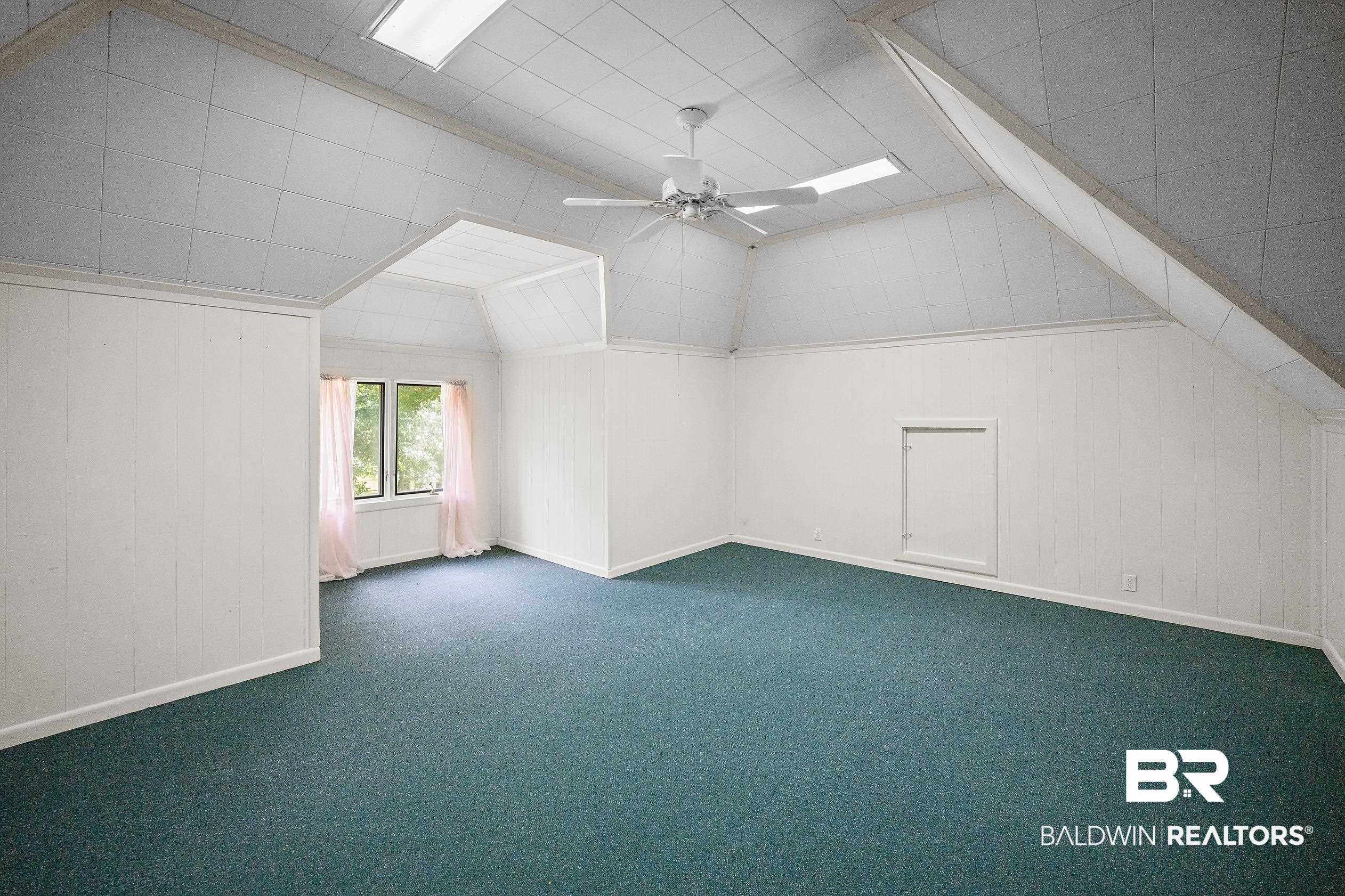 329 Norwood Road Monroeville, AL 36460 - Photo 33 of 49 Spacious room featuring vaulted ceilings with recessed lighting, green carpeting, white paneled walls, and a ceiling fan