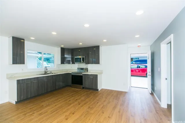 a large kitchen with stainless steel appliances granite countertop a sink and cabinets with wooden floor