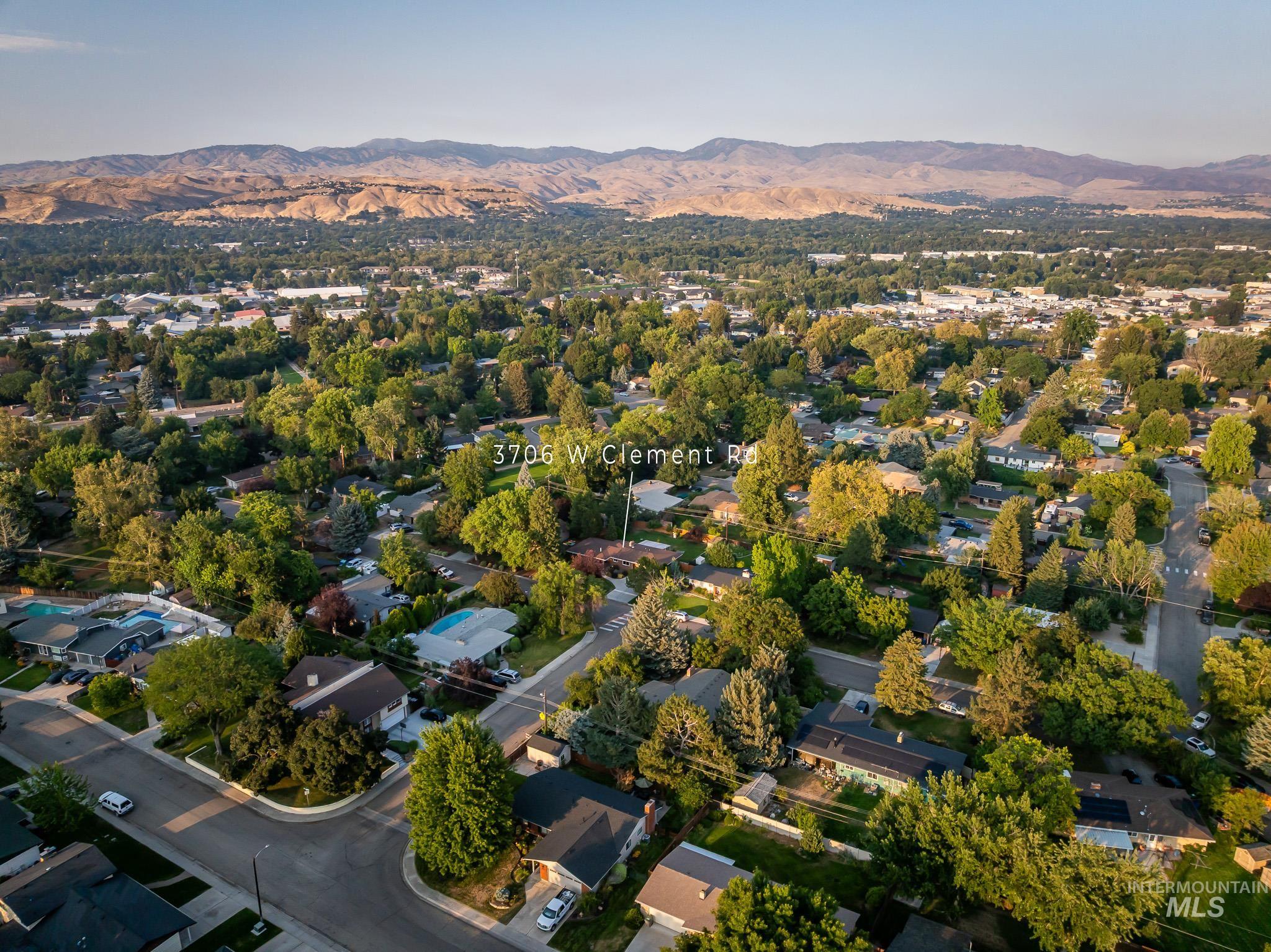 3706 West Clement Road Boise, ID 83704 - Photo 34 of 36 Aerial perspective of this tree-lined residential neighborhood showcasing mature landscaping, established single-family homes, and rolling foothills in the distance