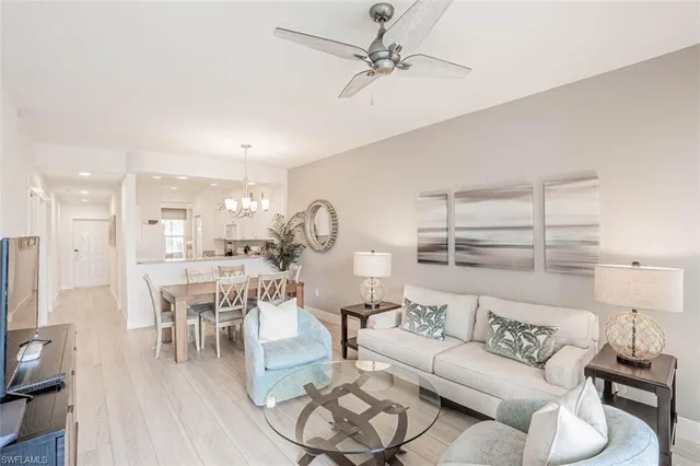 a living room with furniture kitchen view and a wooden floor