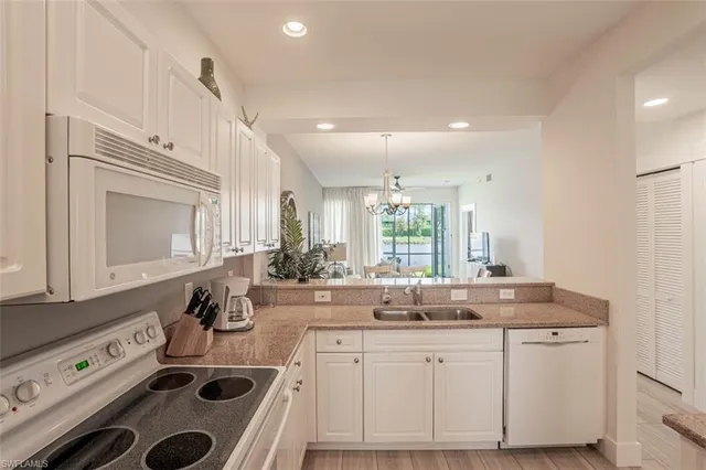 a kitchen with sink a stove and white cabinets with wooden floor