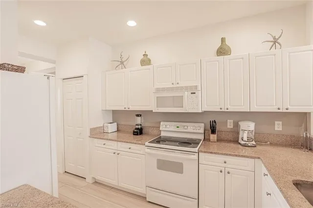 a kitchen with stainless steel appliances granite countertop a sink a stove and white cabinets