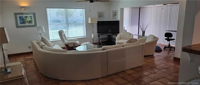 a living room with furniture a flat screen tv and windows