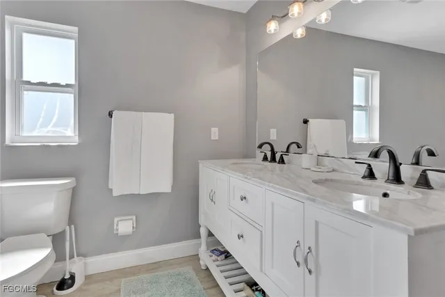 a bathroom with 2 sink toilet and a mirror