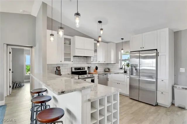 a kitchen with stainless steel appliances granite countertop a sink a stove a refrigerator cabinets and chairs