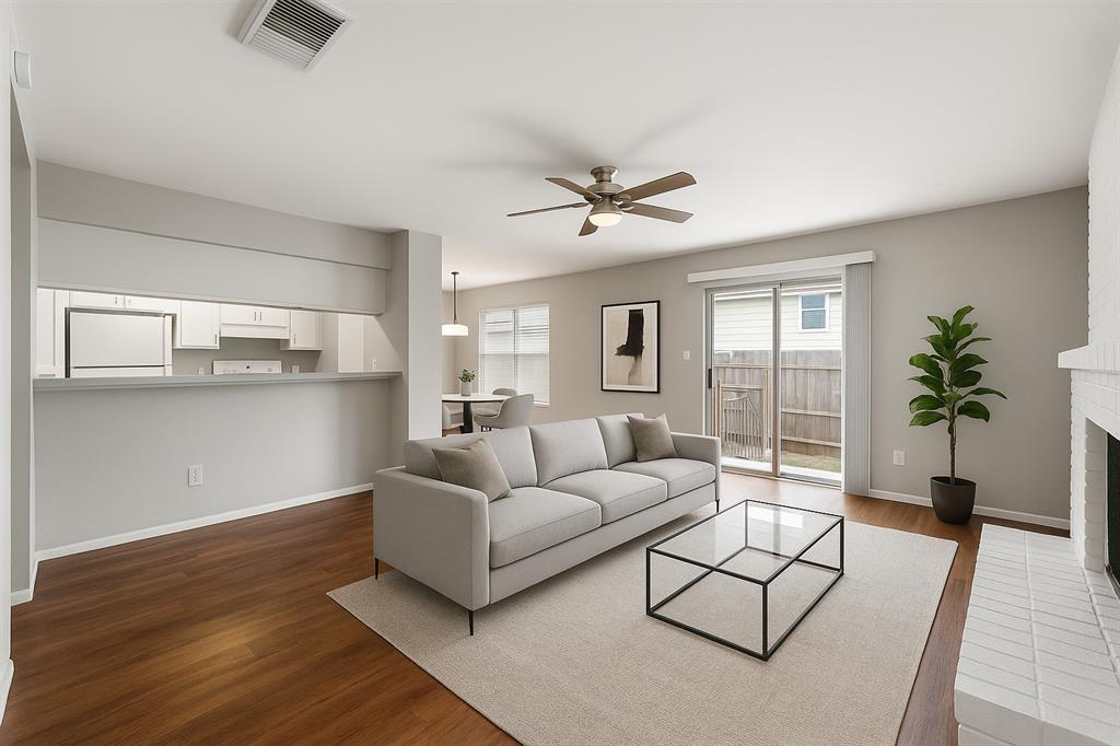 Living area featuring dark wood-type flooring, a ceiling fan, and a fireplace