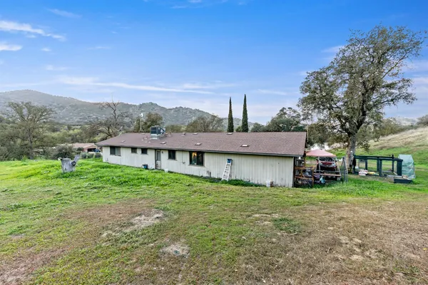 a view of a house with a big yard and large tree