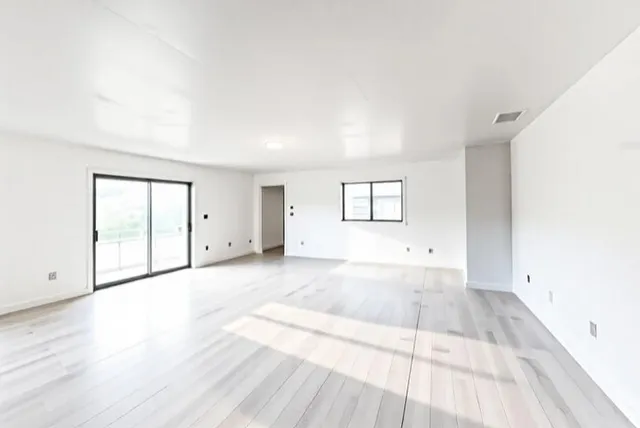 an empty room with wooden floor and windows
