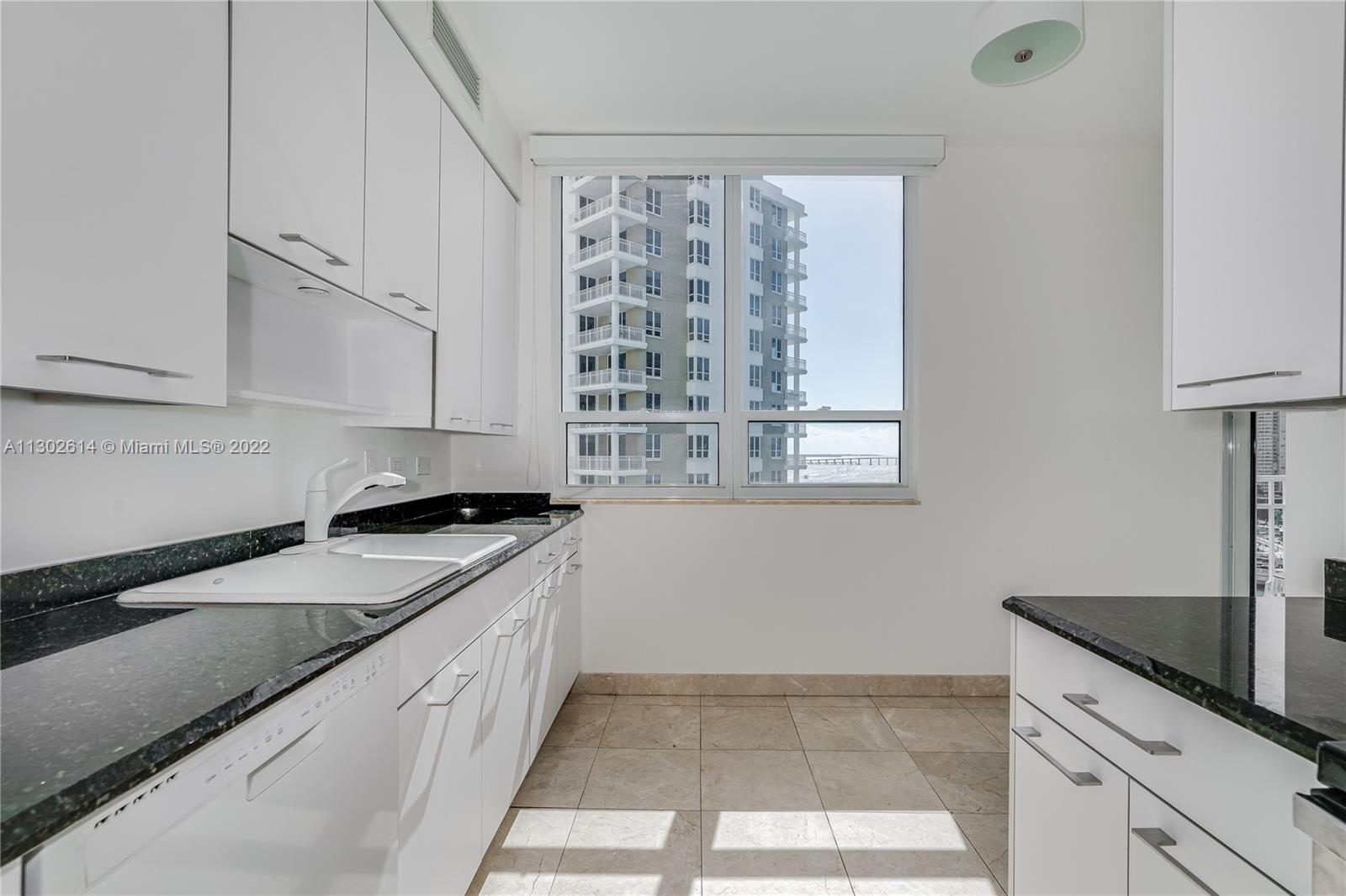 801 Brickell Key Boulevard, Unit 1701 Miami, FL 33131 - Photo 13 of 32 a kitchen with granite countertop a sink a stove and cabinets