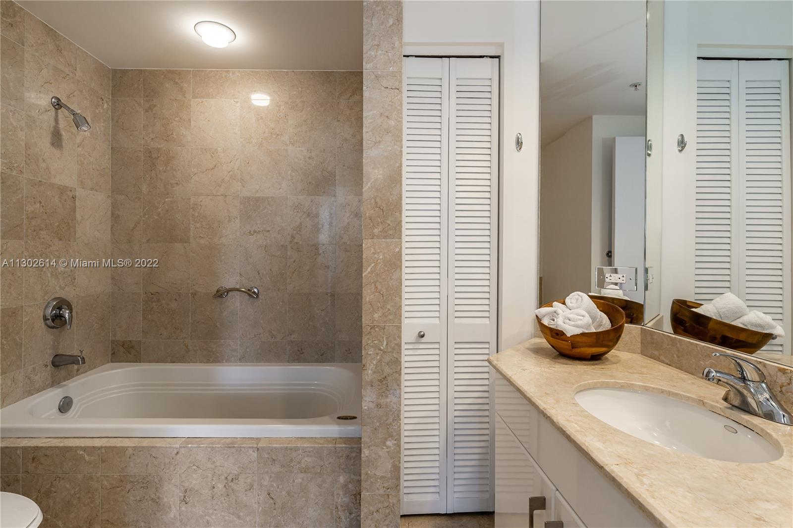 801 Brickell Key Boulevard, Unit 1701 Miami, FL 33131 - Photo 18 of 32 a bathroom with a granite countertop sink and a bathtub