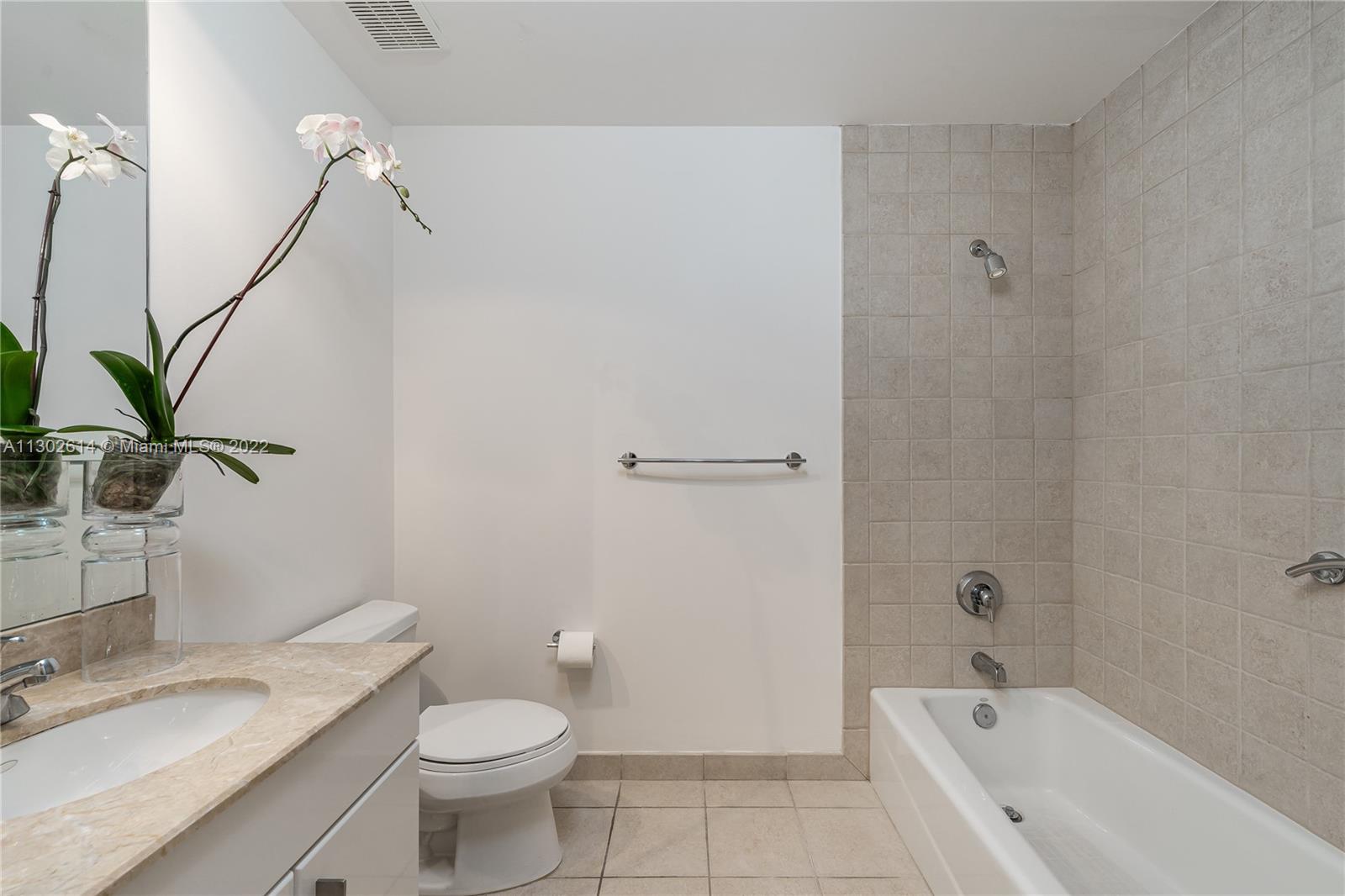 801 Brickell Key Boulevard, Unit 1701 Miami, FL 33131 - Photo 22 of 32 a bathroom with a granite countertop sink a toilet and bathtub