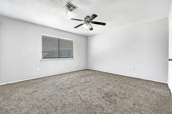 an empty room with a window and a fan