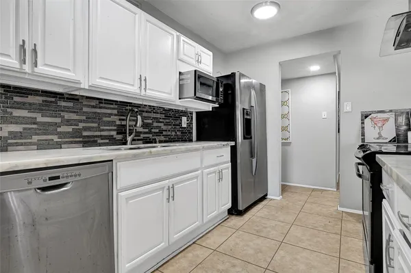 a kitchen with stainless steel appliances granite countertop a refrigerator sink and white cabinets