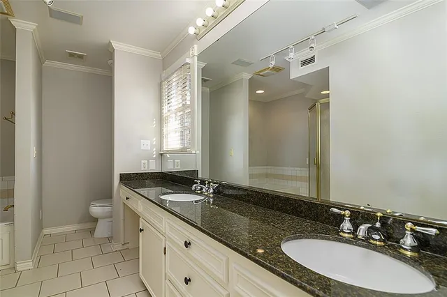 a bathroom with a granite countertop double vanity sink a mirror and a toilet