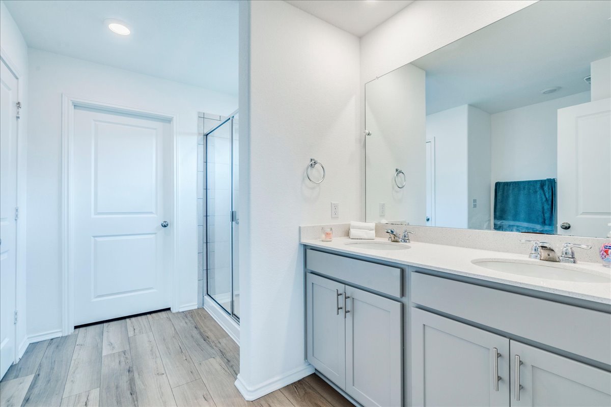 389 Salt Springs Road Kyle, TX 78640 - Photo 16 of 30 Modern bath offering dual vanities, large mirror, and a glass-enclosed shower.