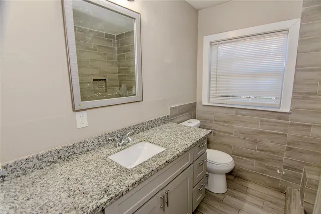 a bathroom with a granite countertop toilet sink and mirror