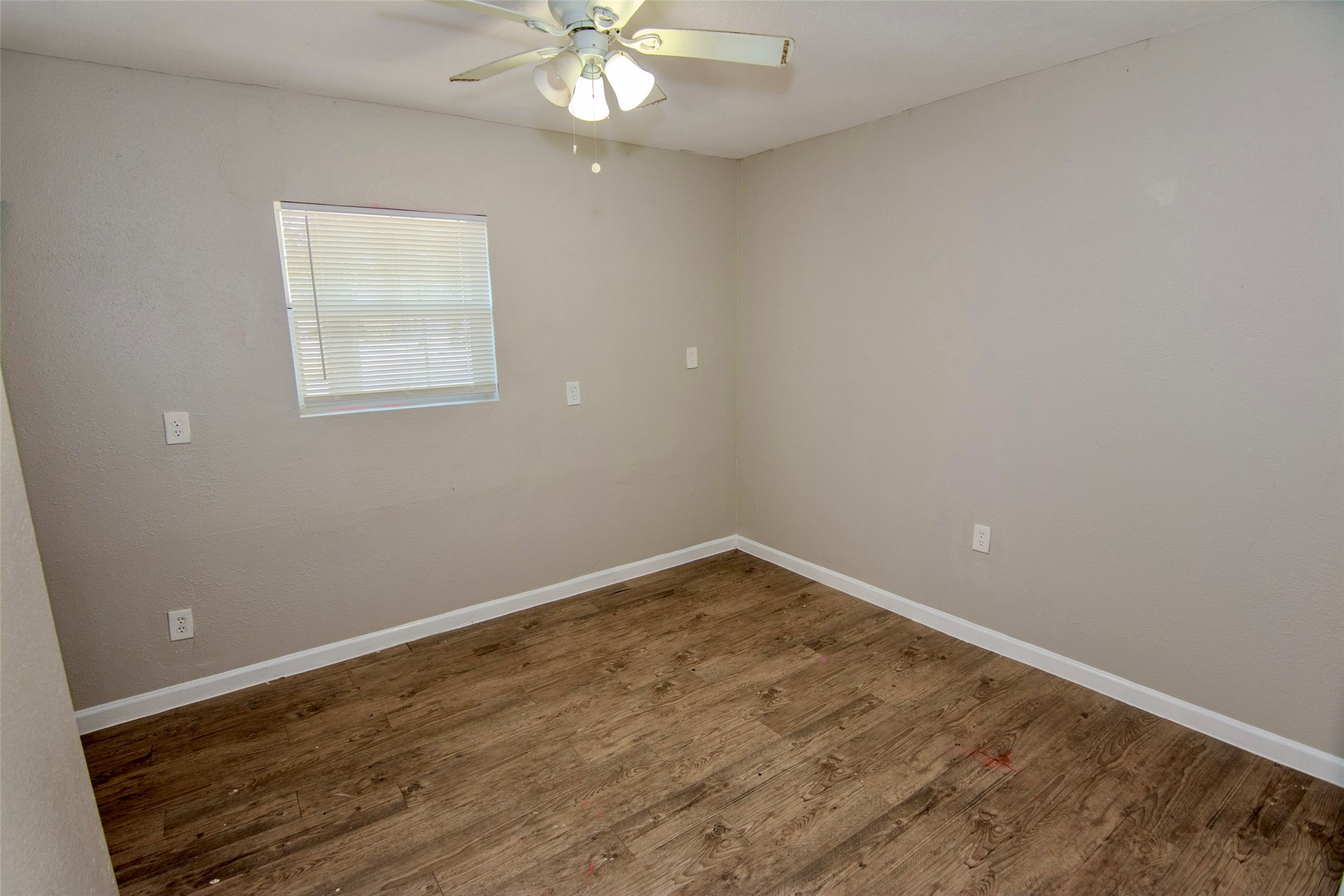 904 Mobile Drive Pasadena, TX 77506 - Photo 8 of 13 an empty room with wooden floor and fan