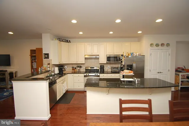 a kitchen with kitchen island granite countertop a sink counter top space appliances and cabinets