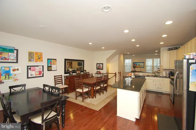 a living room with stainless steel appliances furniture a flat screen tv and a kitchen view