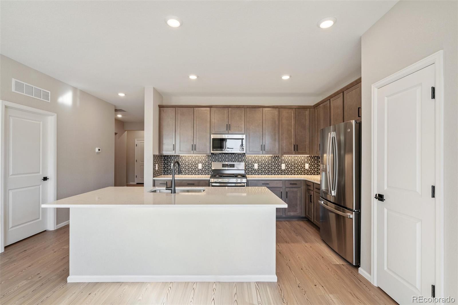 2155 Farmlore Drive Brighton, CO 80601 - Photo 18 of 41 a kitchen with stainless steel appliances granite countertop a refrigerator a stove top oven a sink and dishwasher with wooden floor