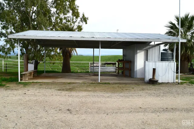 a view of a patio with table and chairs under an umbrella with a small yard