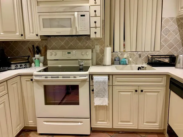 a kitchen with white cabinets and white appliances