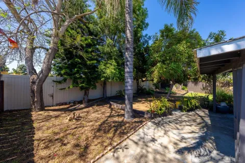 a backyard of a house with table and chairs under an umbrella