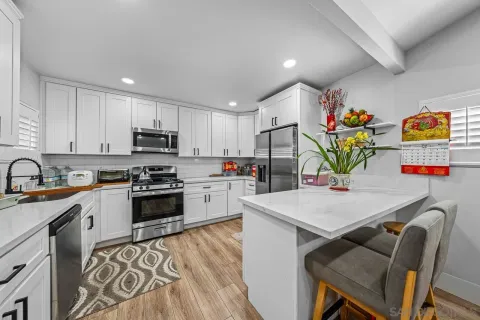 a open kitchen with stainless steel appliances granite countertop a sink dishwasher stove refrigerator and microwave with wooden floor