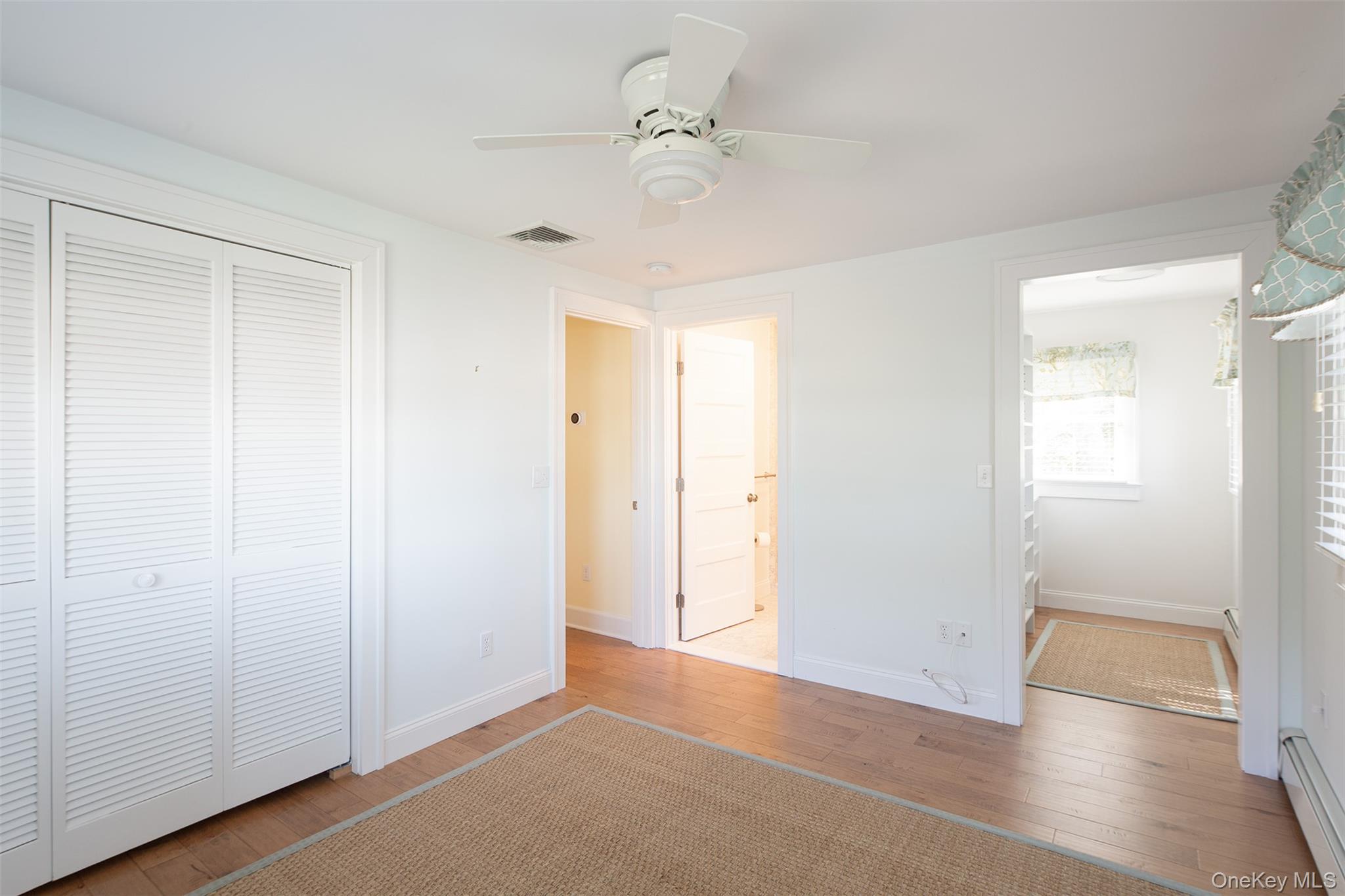 1 Canal Road Hampton Bays, NY 11946 - Photo 29 of 50 Unfurnished bedroom featuring hardwood / wood-style floors, baseboard heating, a closet, a ceiling fan, and ensuite bath