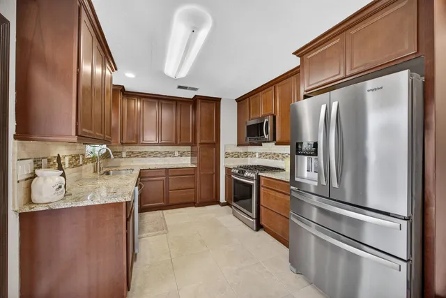 a kitchen with stainless steel appliances granite countertop a refrigerator sink and stove