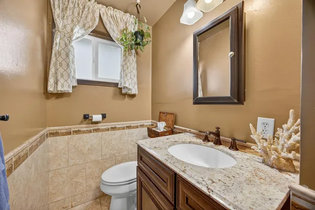 a bathroom with a granite countertop sink a toilet and a mirror