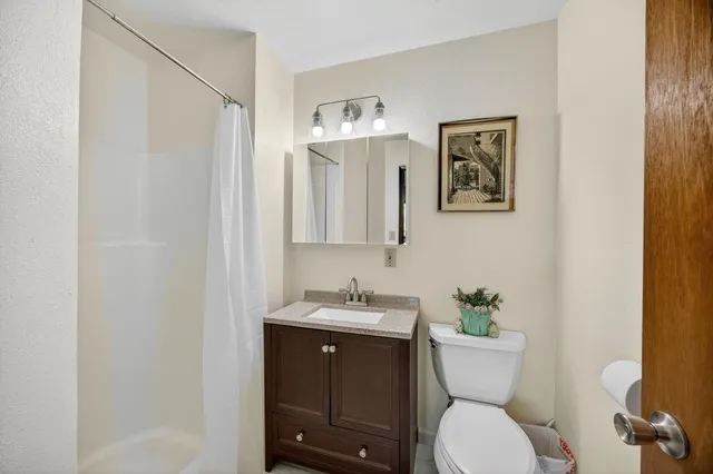 a bathroom with a granite countertop sink a mirror and shower