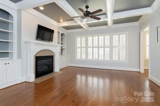 a view of a livingroom with a fireplace a ceiling fan and wooden floor
