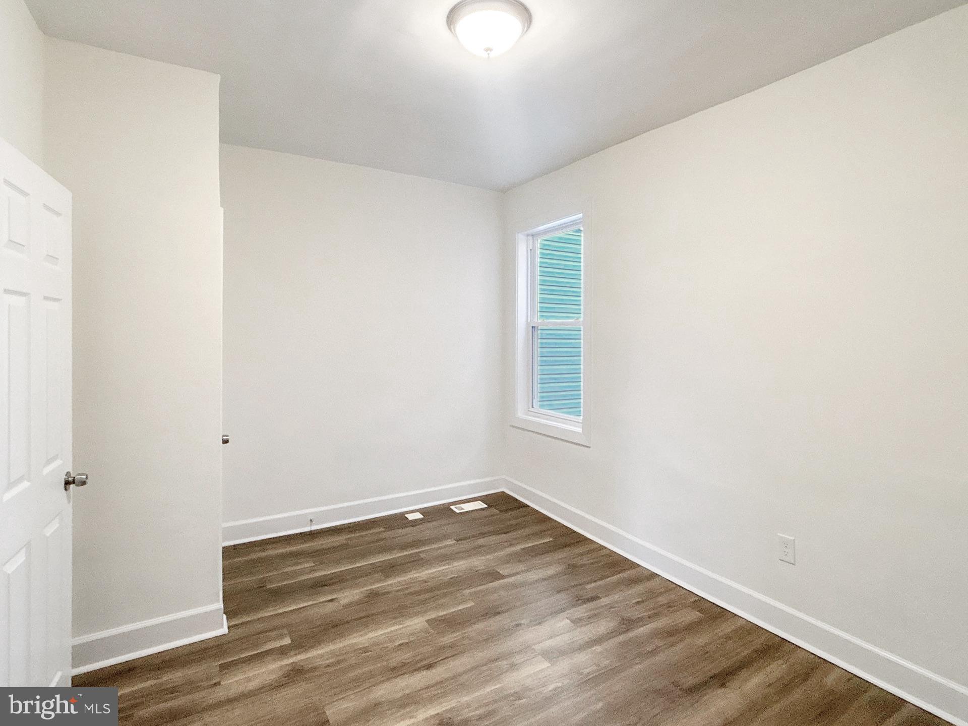 2217 Riggs Avenue Baltimore, MD 21216 - Photo 20 of 26 an empty room with wooden floor and windows