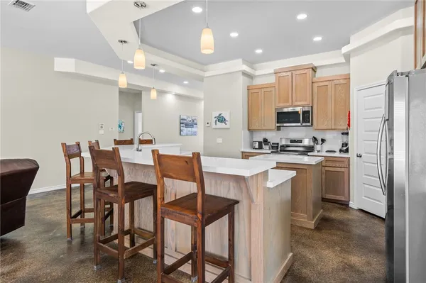 a kitchen that has a lot of cabinets in it with stainless steel appliances a dining table and chairs