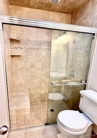a white toilet sitting next to a shower