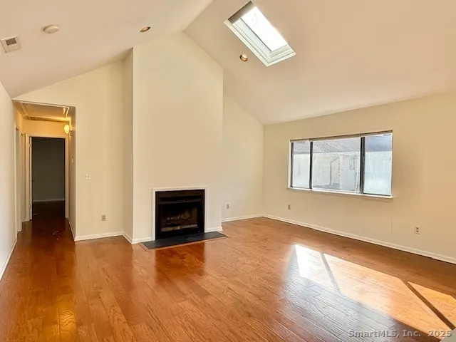 an empty room with wooden floor cabinet and windows