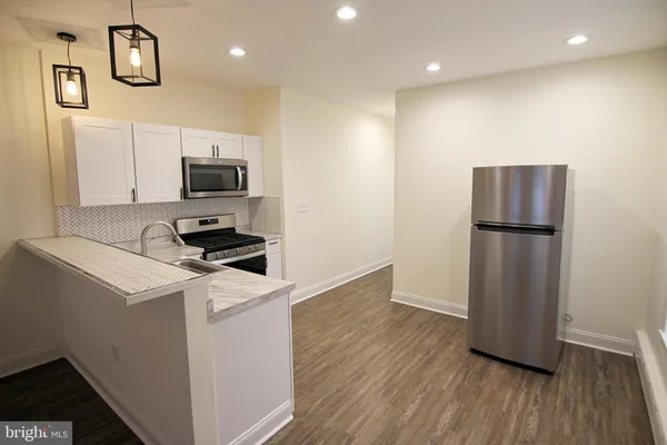 a kitchen with stainless steel appliances a sink cabinets and wooden floor