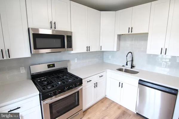 a kitchen with granite countertop a sink stove and microwave