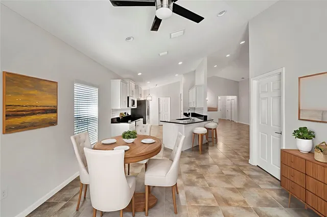 a dining room with stainless steel appliances kitchen island granite countertop a dining table chairs and a refrigerator