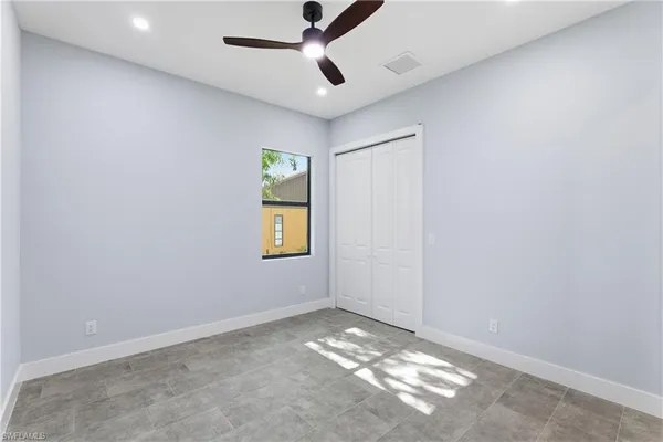 en empty room with windows and ceiling fan