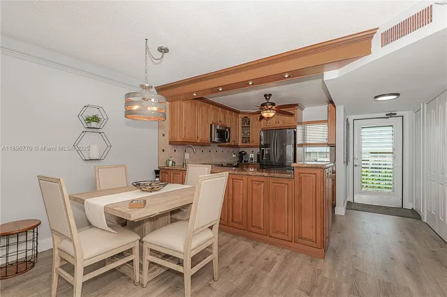 a kitchen with stainless steel appliances kitchen island granite countertop a table chairs in it and wooden floors