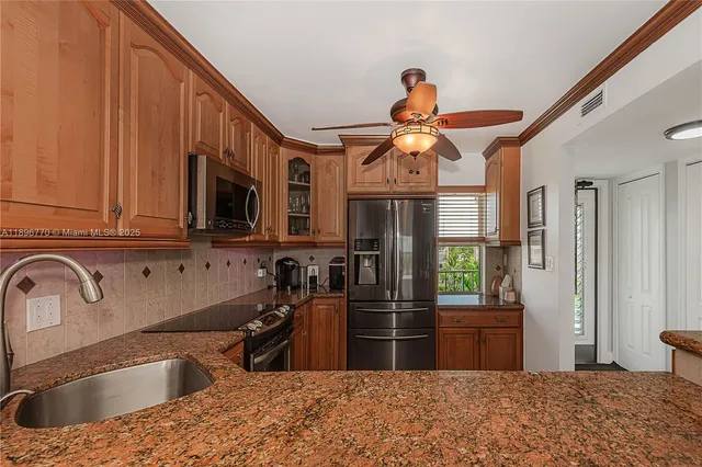 a kitchen with stainless steel appliances granite countertop a sink a stove and a refrigerator