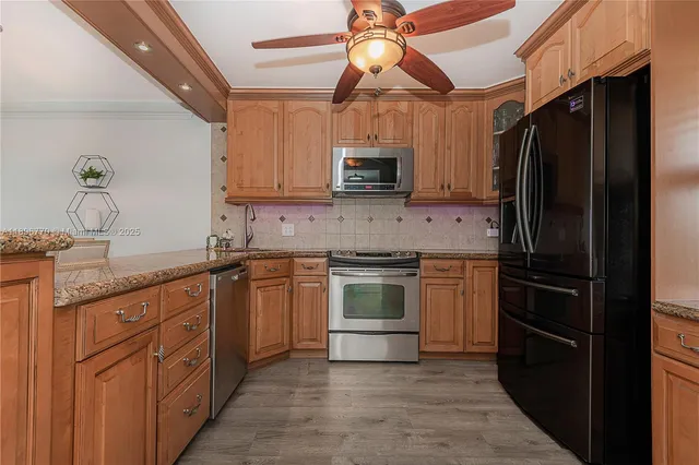 a kitchen with stainless steel appliances granite countertop a refrigerator a stove top oven a sink and dishwasher