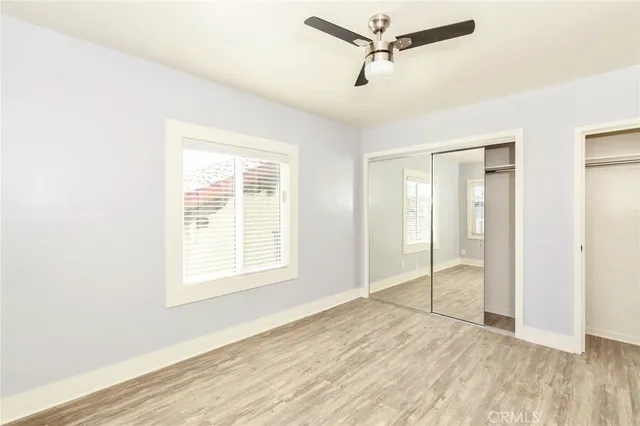 a view of an empty room with wooden floor and closet